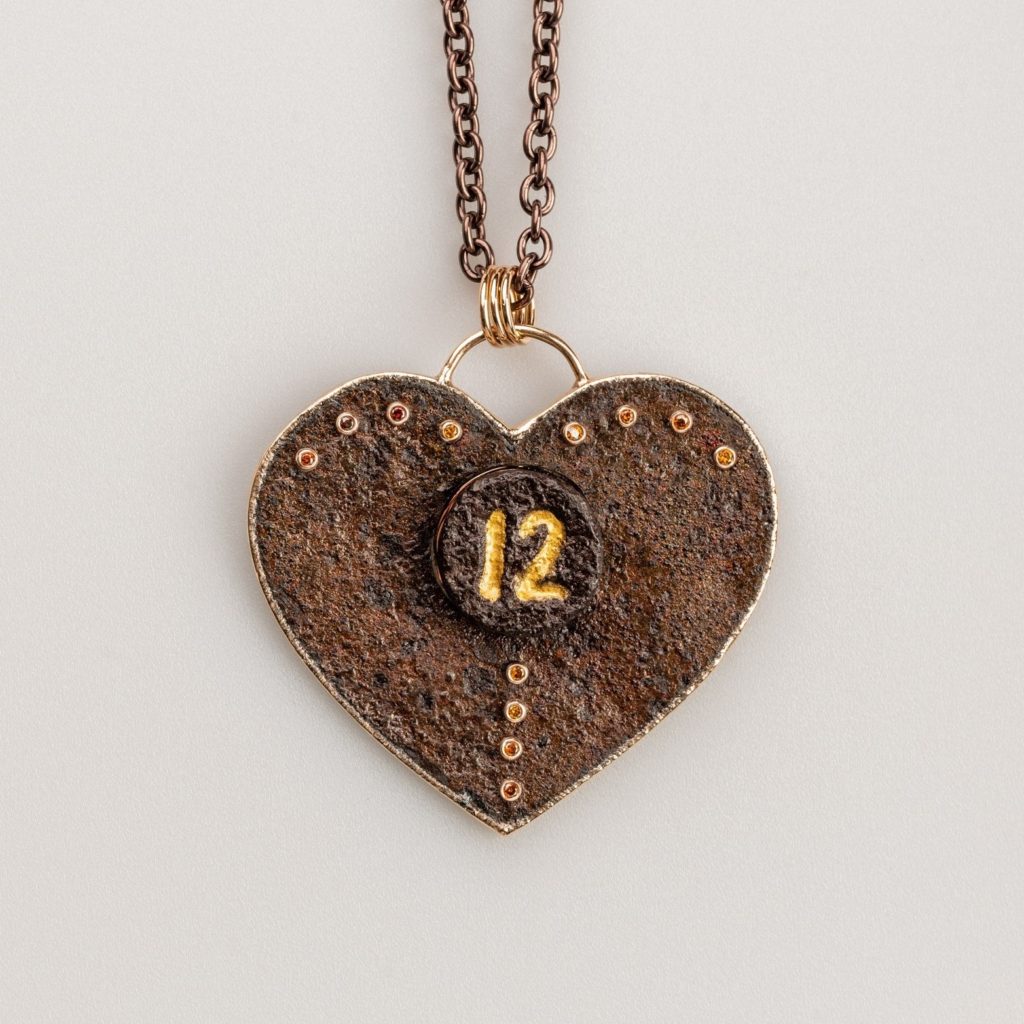 Mixed metal custom necklace with heart shaped pendant with "12" engraved in the center.